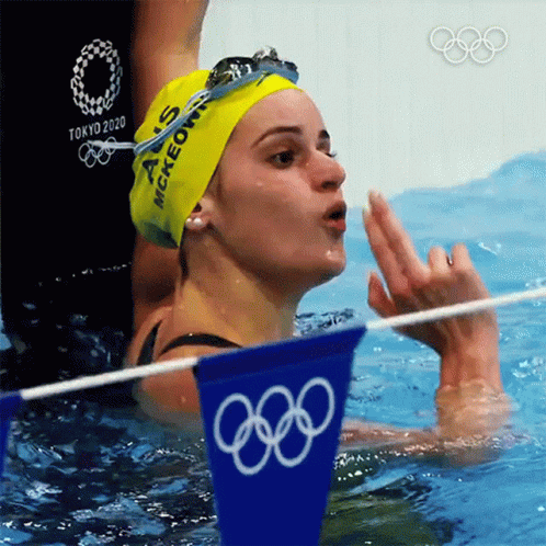 a female swimming in water while holding a towel