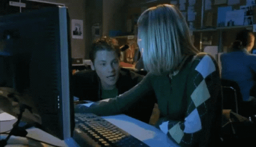 a woman and boy sitting in front of a computer monitor