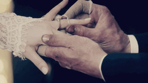 a couple holding hands while putting a wedding ring on another mans hand
