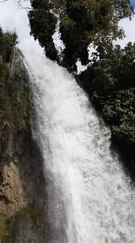 a person standing at the top of a waterfall, in front of a large body of water