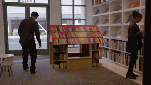 two men are looking at the book shelf