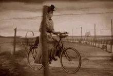 a man on a bike next to a wooden fence