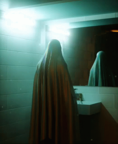 a dark person in a blue cloak standing in a room