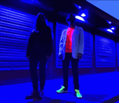 two men and woman standing side by side with the red and blue lighting above them