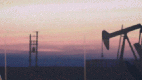 an oil pump at sunset with power lines and telephone poles