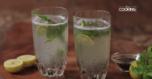 two glasses with colored water and mint next to sliced lemons
