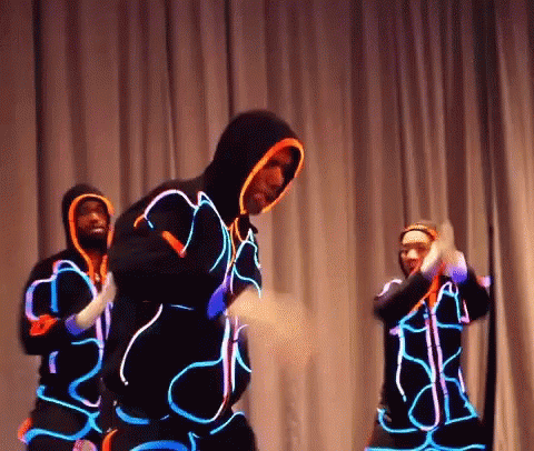 three performers with neon lights are performing
