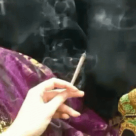 a woman with dark hair holding a cigarette