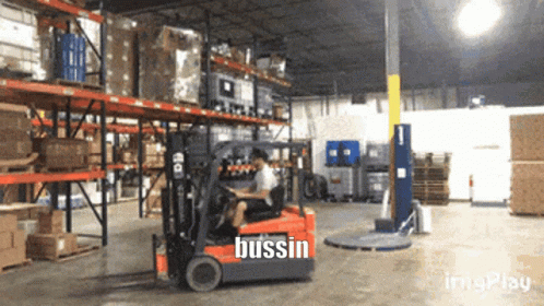 an industrial warehouse with a man driving a small forklift