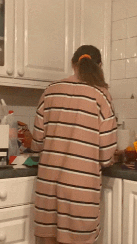 a man standing at a kitchen counter in a blue striped shirt