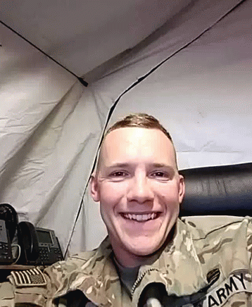 a soldier sitting in a tent with two small dogs