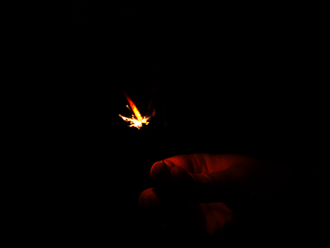 two hands holding an object in the dark