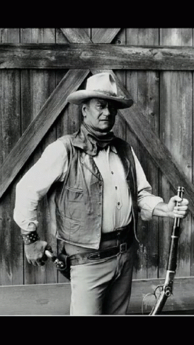 black and white pograph of man in cowboy outfit and holding gun