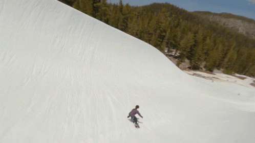 the man is snowboarding down a large hill
