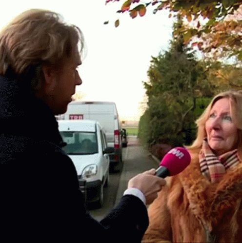a woman speaking to a reporter on the side of the street