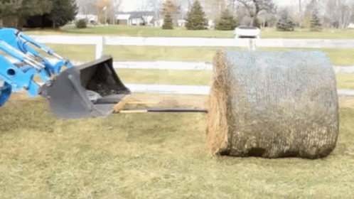 a tractor pulling hay behind a hay bale