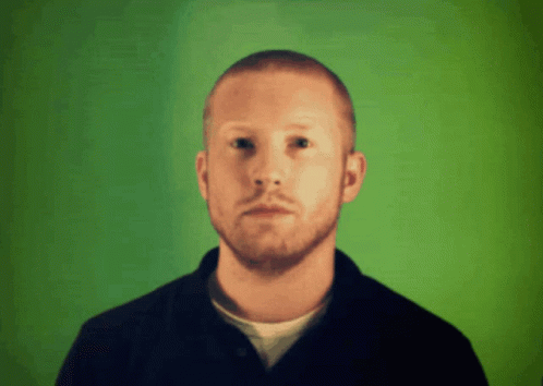 a man with a bald head standing in front of green background