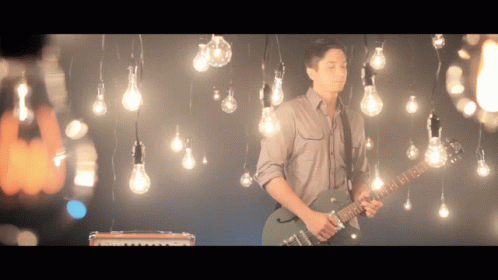 a man with a guitar is performing in front of many lights