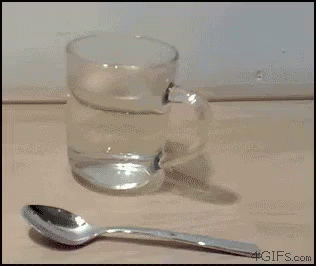 a glass filled with water and a spoon sitting next to it