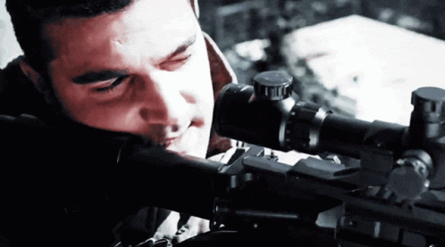 a man looks through the scope of a rifle at the sight line