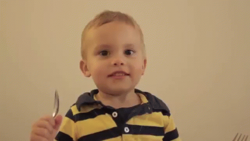 there is a little boy that is holding some knife and fork