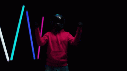 a person standing holding a frisbee in front of three glowing neon sticks