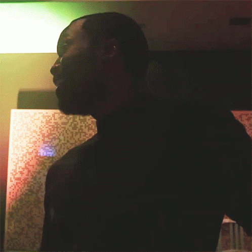 man with black shirt standing in room lit up at night