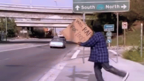 a man walking down the street carrying a sign