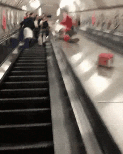 a bunch of people on escalators with one person walking