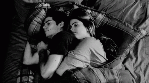 a black and white image of two people laying on pillows