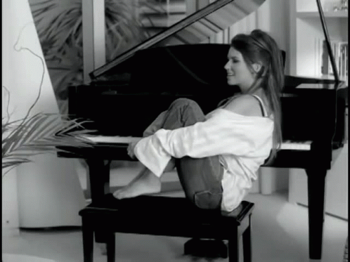 a girl sitting in front of a piano while reading