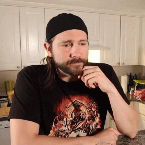 a man with a beard sits in the kitchen
