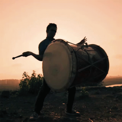 a young man is playing an african drum