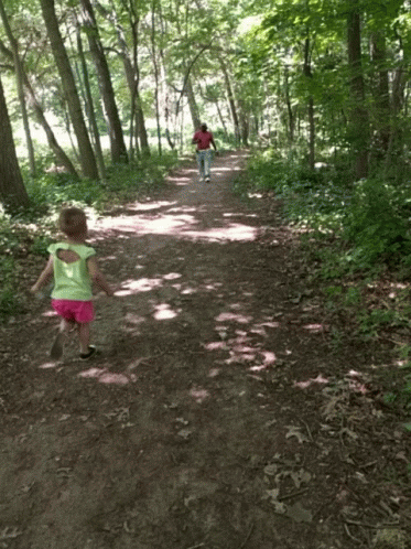 two children walking along a path in the woods