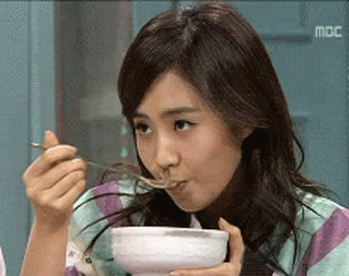 a woman eating soup from a white bowl