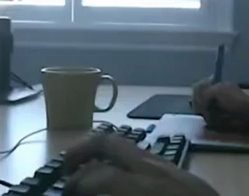 a computer desk with a keyboard, coffee mug and a mouse on it