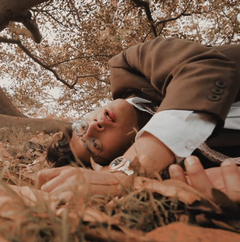 a person laying in the grass with trees
