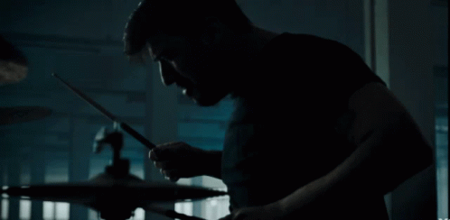 a man plays drums in a dark room