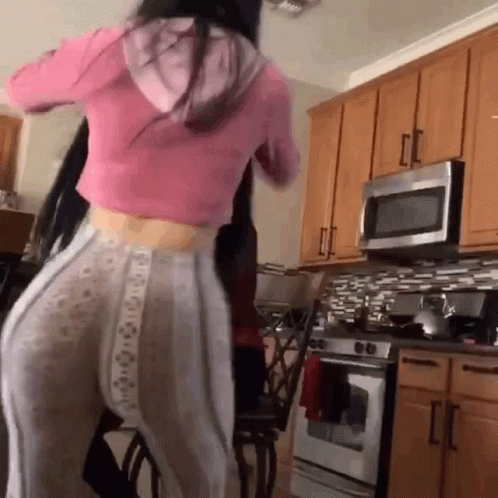 a woman standing in a kitchen wearing wide pants
