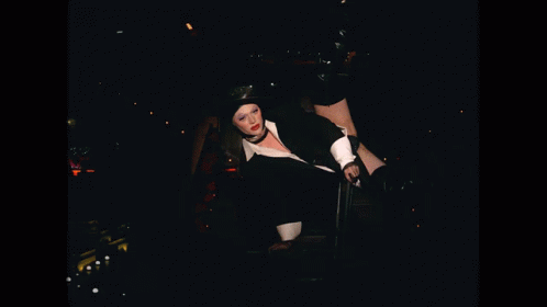 a young woman wearing a hat is sitting in the dark