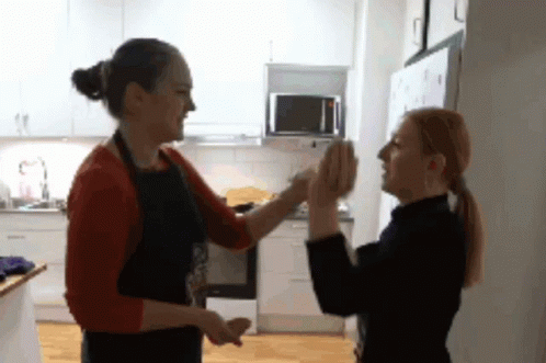 two woman standing near each other in a kitchen