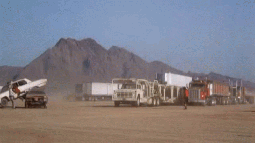 a desert landscape with mountains and trucks