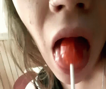 an odd s of a young woman biting into a lollypop