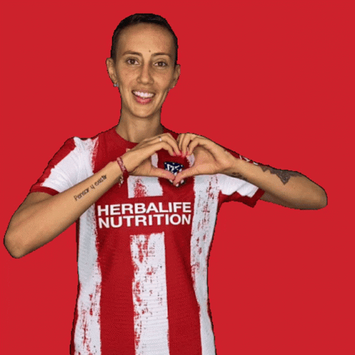 a woman wearing a jersey holds up a heart in her hands