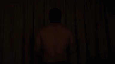 a man standing at the corner in the dark in a room