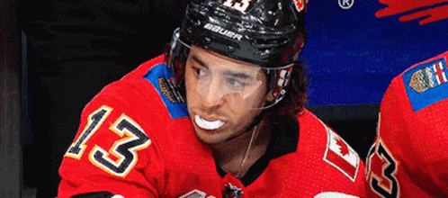 a hockey player wearing all blue with his face painted like a demon