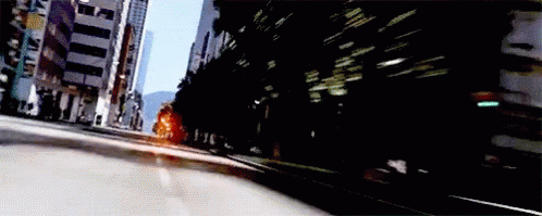 an blurry image shows the back end of a car passing by some buildings
