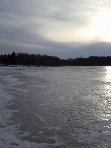 a man walking across a frozen lake under an ominous sky