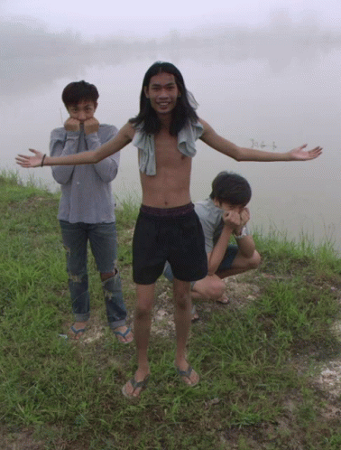 three people pose in front of a body of water