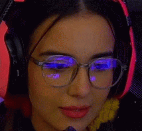 a woman with glasses is wearing red light blocking headphones